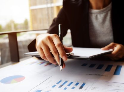 female manager putting his ideas and writing business plan at workplace,woman holding pens and papers, making notes in documents, on the table in office,vintage color,morning light ,selective focus.